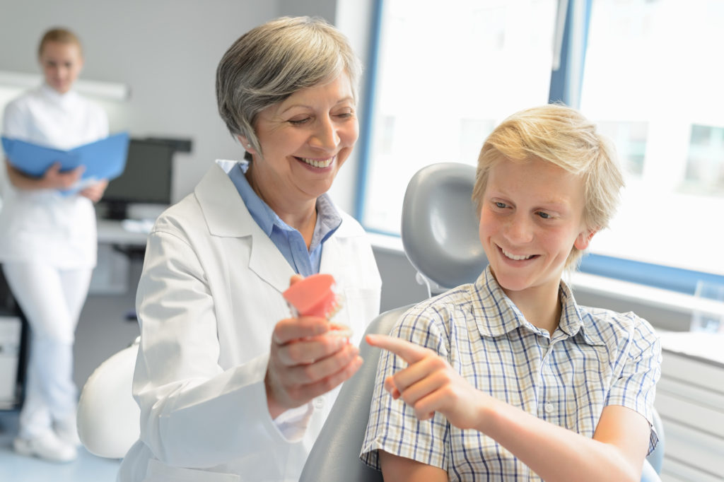Pediatric Dentist Showing teeth model to a kid