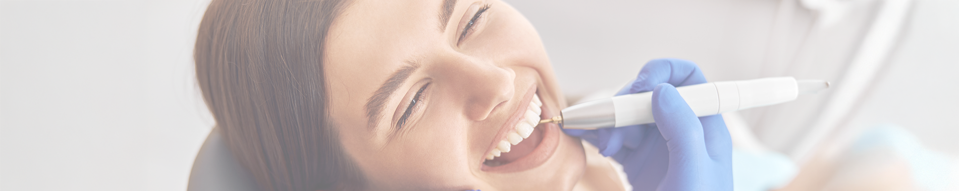 A woman receiving a dental cleaning from a dentist in a clinical setting, showcasing oral hygiene practices.